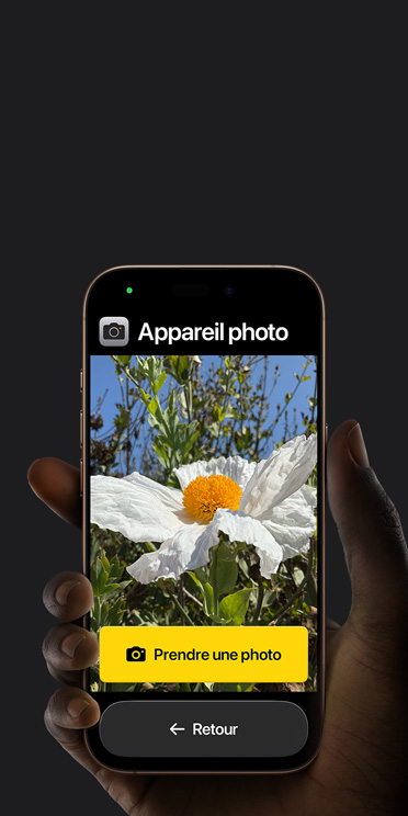 Écran d’un iPhone 16 Pro montrant l’interface simplifiée de l’app Appareil photo. Une fleur rose est dans le cadre et le bouton Prendre une photo et celui de retour sont en dessous.