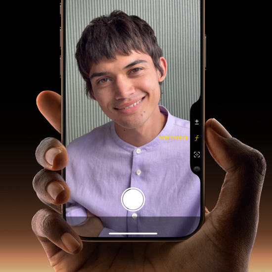 Main tenant un iPhone 16 Pro titane sable, et dont le pouce glisse sur la commande de la caméra pour régler la profondeur de champ