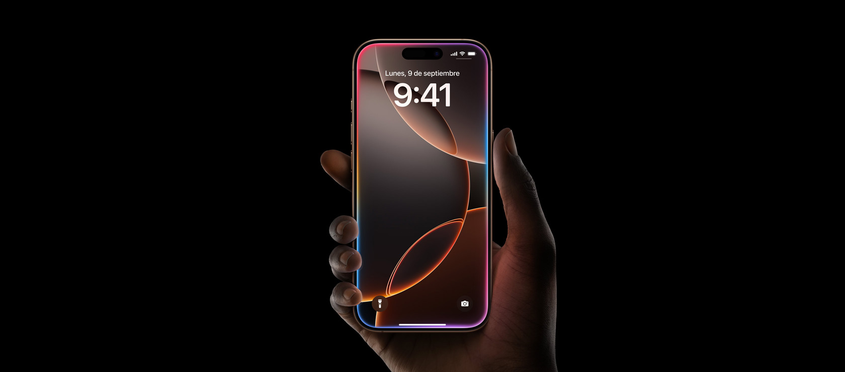 Una mano sujeta un iPhone 16 Pro en titanio color desierto que muestra la pantalla de borde a borde, la Dynamic Island centrada en la parte superior y las esquinas redondeadas