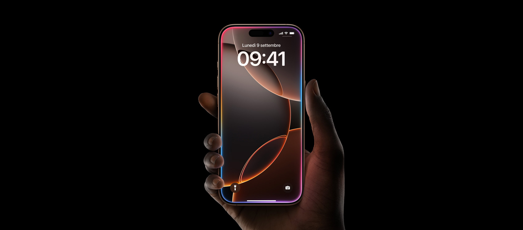  Una mano che tiene un iPhone 16 Pro color titanio sabbia, display all-screen con Dynamic Island al centro verso il bordo superiore, angoli arrotondati