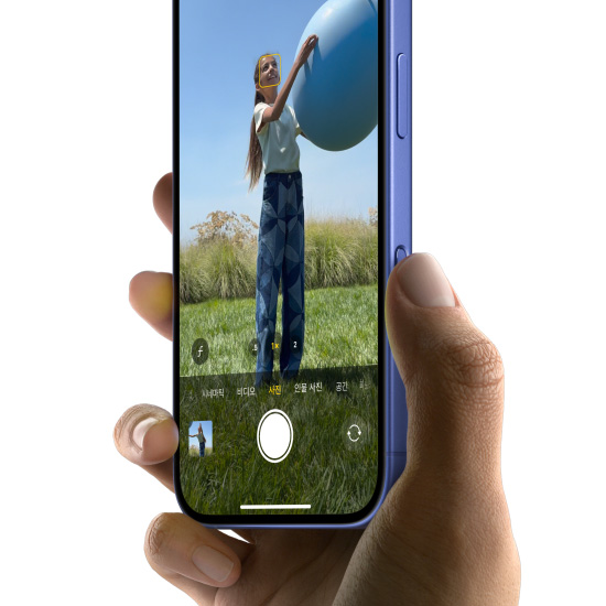 울트라마린 색상의 iPhone 16을 손으로 든 채 카메라 컨트롤 버튼에 엄지를 대고 문지르듯 움직여 사진 기능을 선택하는 모습