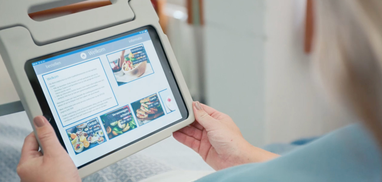 Una paziente che guarda lo schermo di un iPad mentre è seduta nel suo letto d’ospedale.
