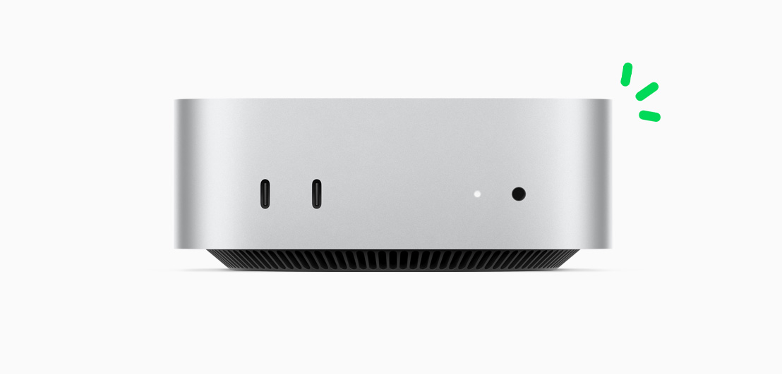 صورة أمامية لجهاز Mac mini باللون الفضي تعرض المنافذ الأمامية وضوء مؤشر التشغيل، مع توضيح قصة الحياد الكربوني من خلال لمسات صغيرة باللون الأخضر.