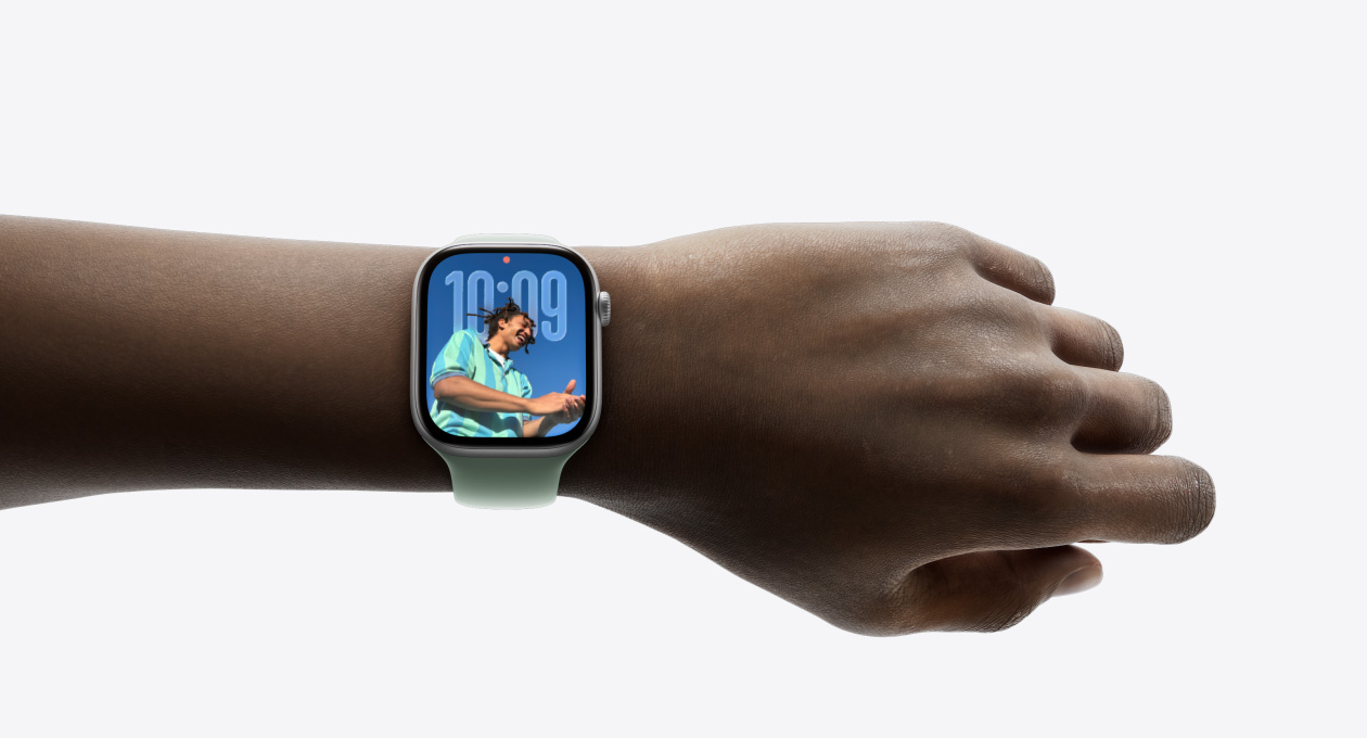 Close-up of Apple Watch in Silver with rubber band on a person’s wrist, showing new Liquid Glass design