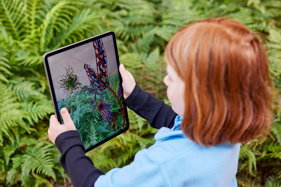 iPad Proを手に、Deep Fieldアプリを使って屋外の植物を探索する若い生徒。