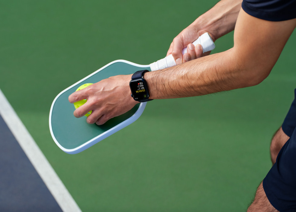 Bir oyuncunun elinde tuttuğu pickleball raketi ve topu gösteriliyor.