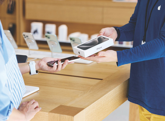 Et bilde som forestiller Apple Trade In, viser en kunde som bytter inn sin gamle iPhone mot en ny telefon i en eske.