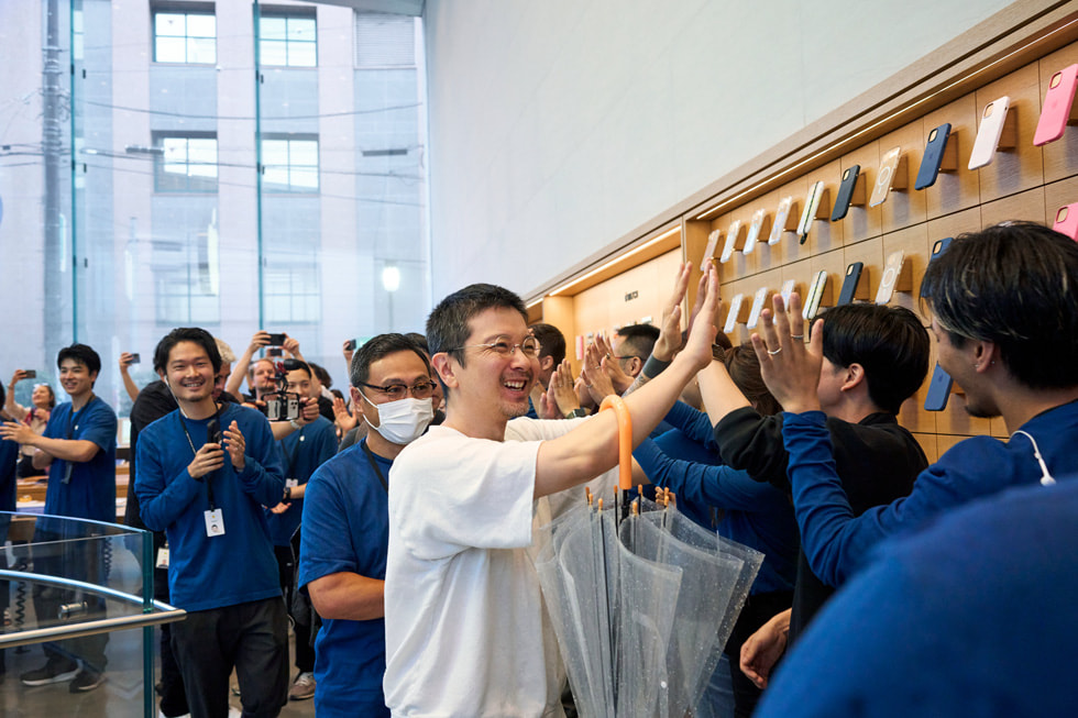 عميل يحيي طابوراً من أعضاء فريق Apple داخل متجر Apple Omotesando.