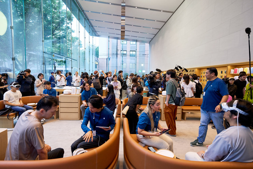 لقطة واسعة تظهر العشرات من العملاء وأعضاء الفريق داخل متجر Apple Omotesando الذي يعج بالحضور.