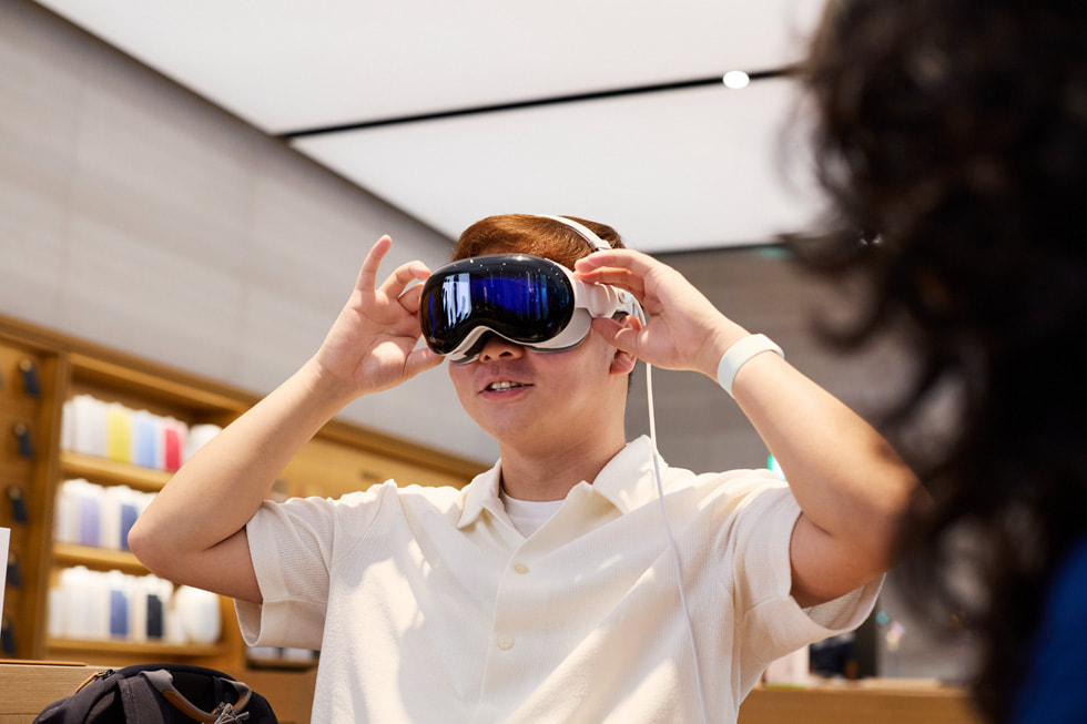 عميل يرتدي Apple Vision Pro ويضع كلتا يديه على جانبي رأسه.