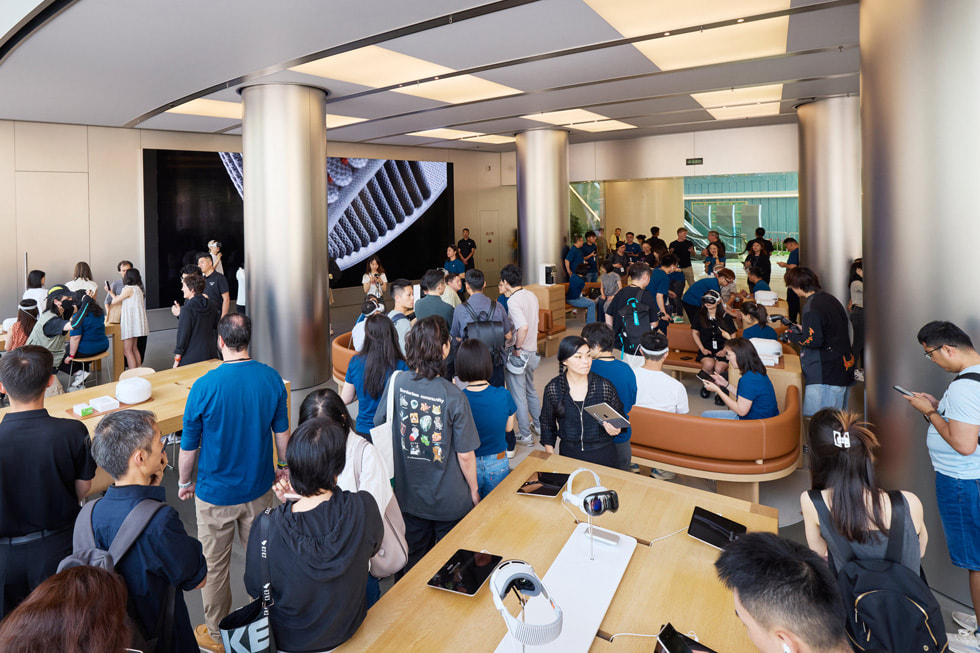 لقطة واسعة من داخل متجر Apple Wangfujing تُظهر العملاء وهم يستكشفون المتجر، مع وجود منطقة العرض التوضيحي في الخلف.