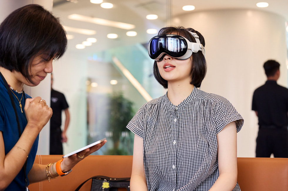 إحدى أعضاء فريق Apple تجلس مع عميلة ترتدي Apple Vision Pro.
