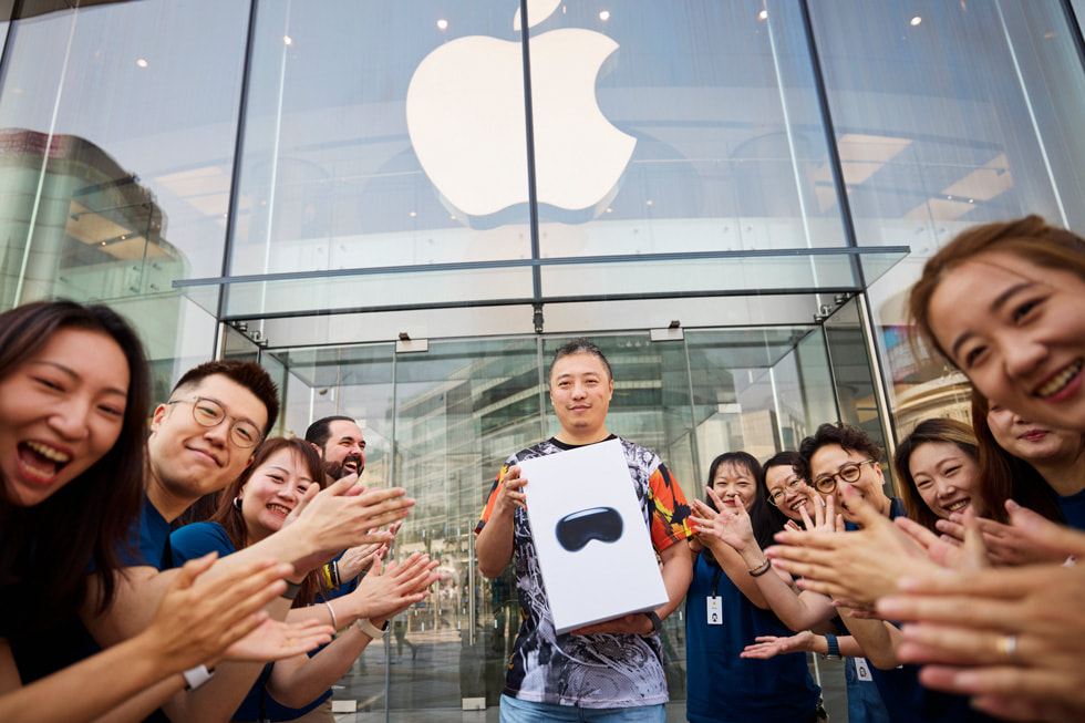 أعضاء الفريق يهتفون أثناء مغادرة عميل يحمل علبة Apple Vision Pro من متجر Apple Wangfujing.