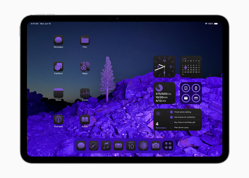 풍경 이미지 배경화면을 둘러싼 연한 보라빛 색조의 앱 아이콘과 위젯을 보여주는 iPad Pro. 