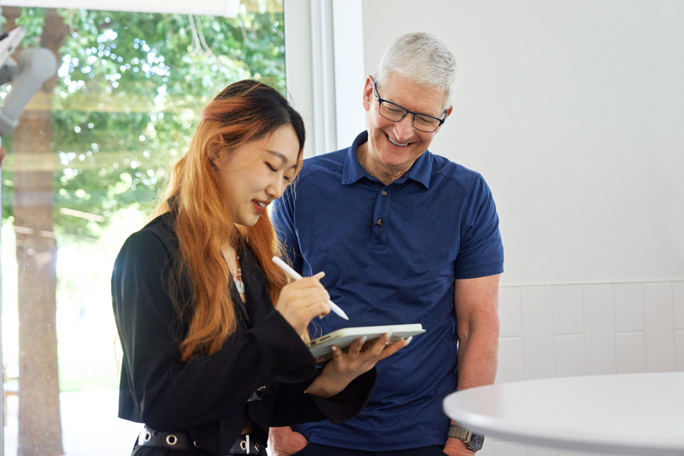Elinde iPad ile Apple Pencil tutan bir geliştiricilik öğrencisinin Tim Cook ile fotoğrafı.