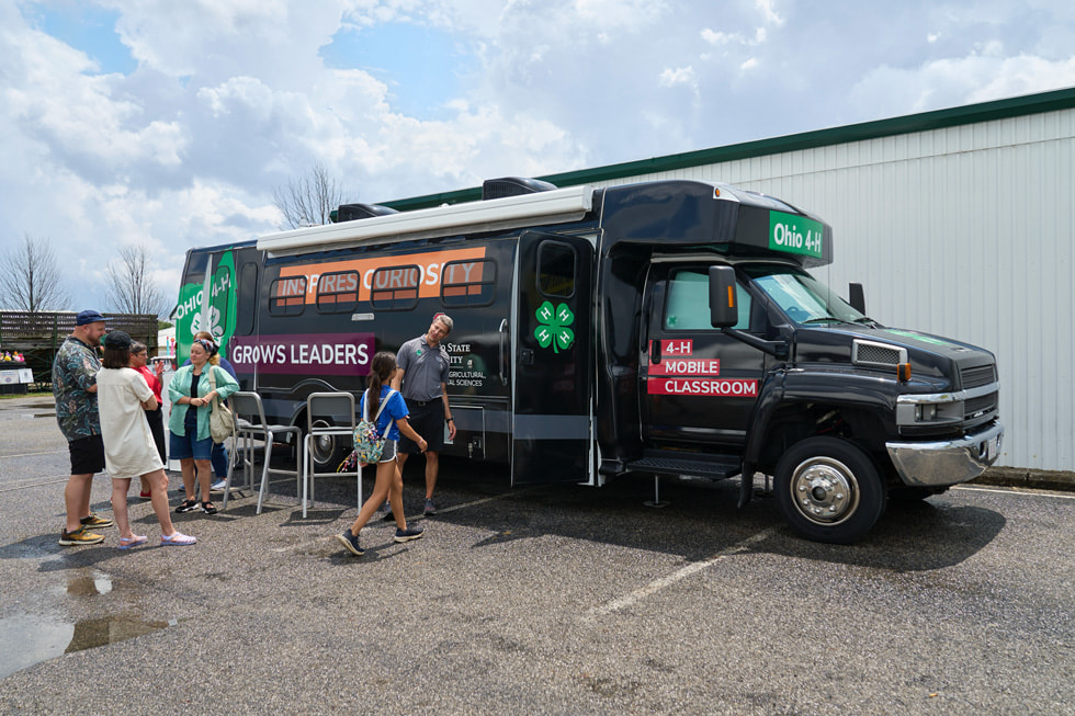Un groupe de jeunes se tient devient un autobus de 4-H converti en classe ambulante.
