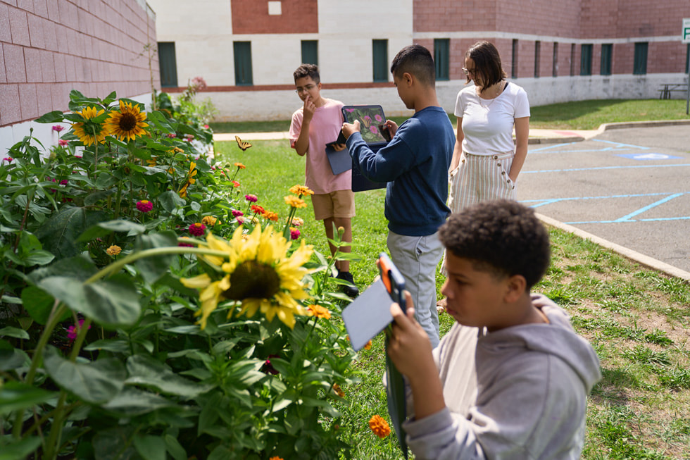 Des personnes participant au camp STEM Explorers utilisent la caméra d’iPad dans un jardin.