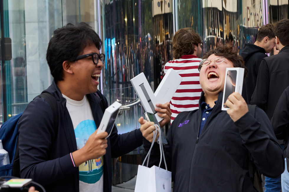 Deux clients rient en montrant leurs nouveaux achats à Apple Fifth Avenue, à New York.