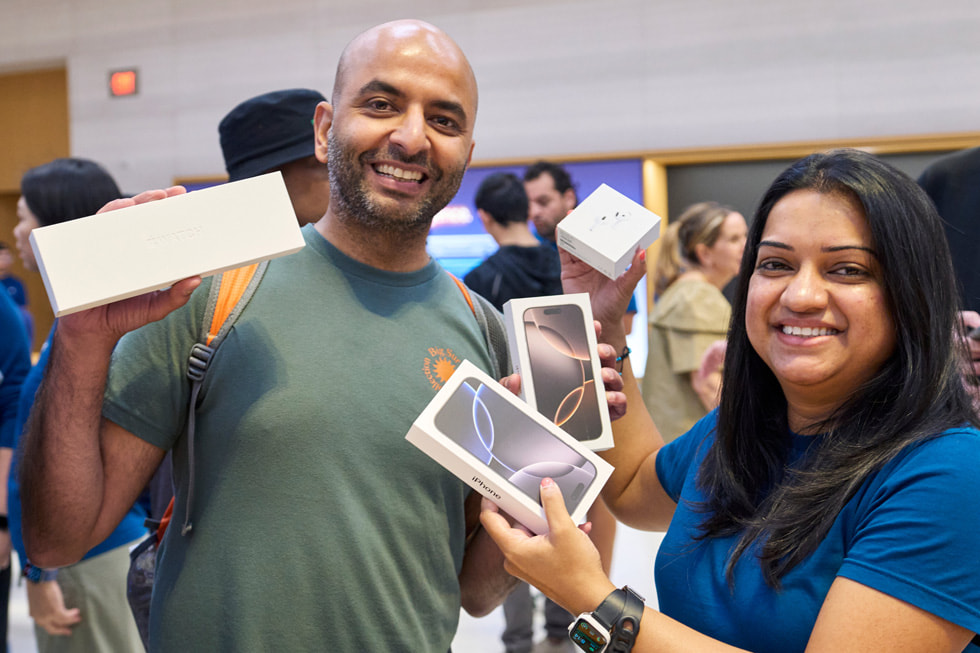 Un client et une employée montrent de nouveaux produits, dont deux issus de la gamme iPhone 16, à Apple Fifth Avenue, à New York.