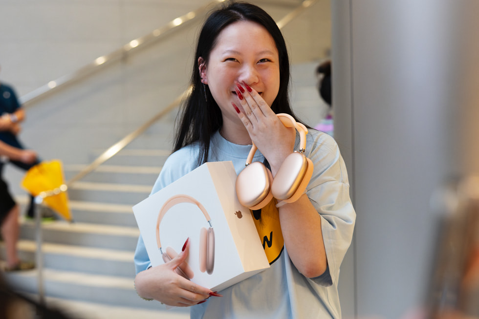 Une cliente sourit timidement avec ses nouveaux AirPods Max.