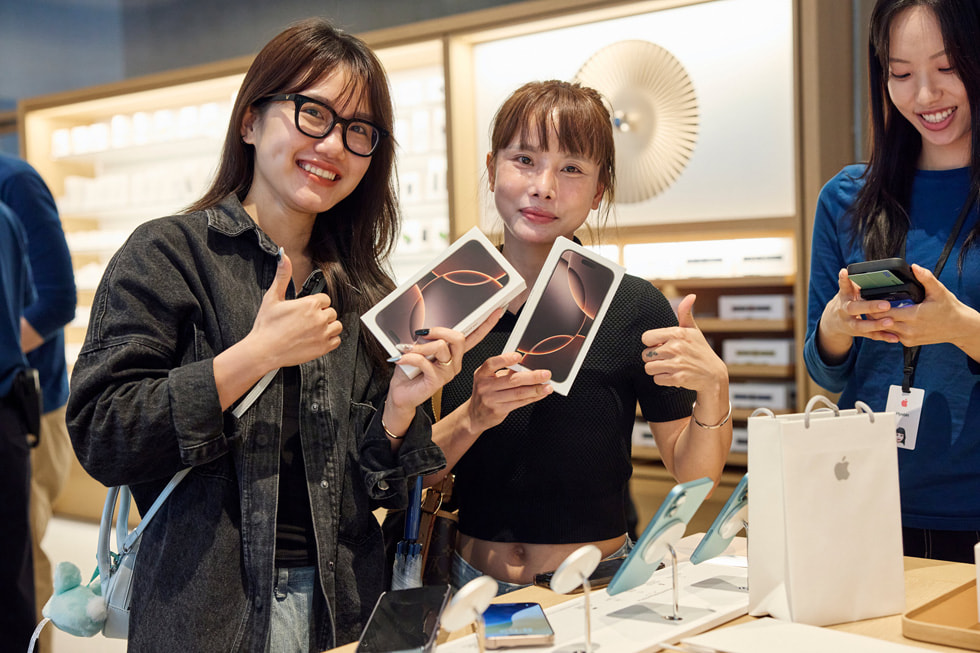 Des clientes montrent leurs nouveaux iPhone 16 Pro.