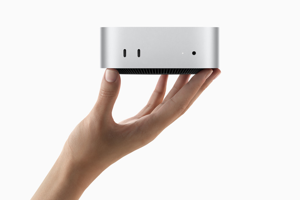 يدٌ تحمل جهاز Mac mini الجديد كلياً.