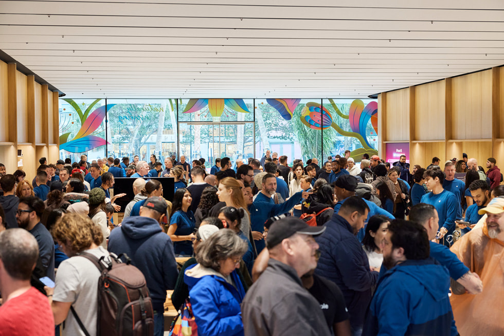 Khách hàng và nhân viên đang đứng cùng nhau trong cửa hàng Apple Miami Worldcenter. 