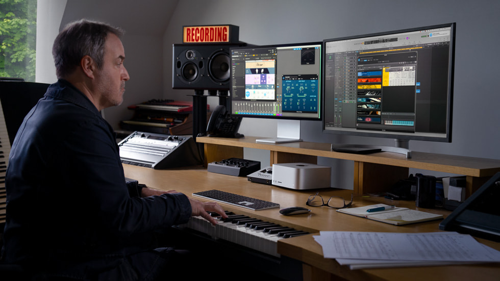 محترف يعمل على مكتبه مع شاشات متعددة متصلة بجهاز Mac Studio.
