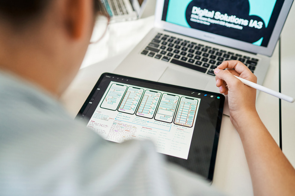 Bir öğrenci iPad, Apple Pencil ve MacBook Air kullanarak uygulama geliştiriyor.