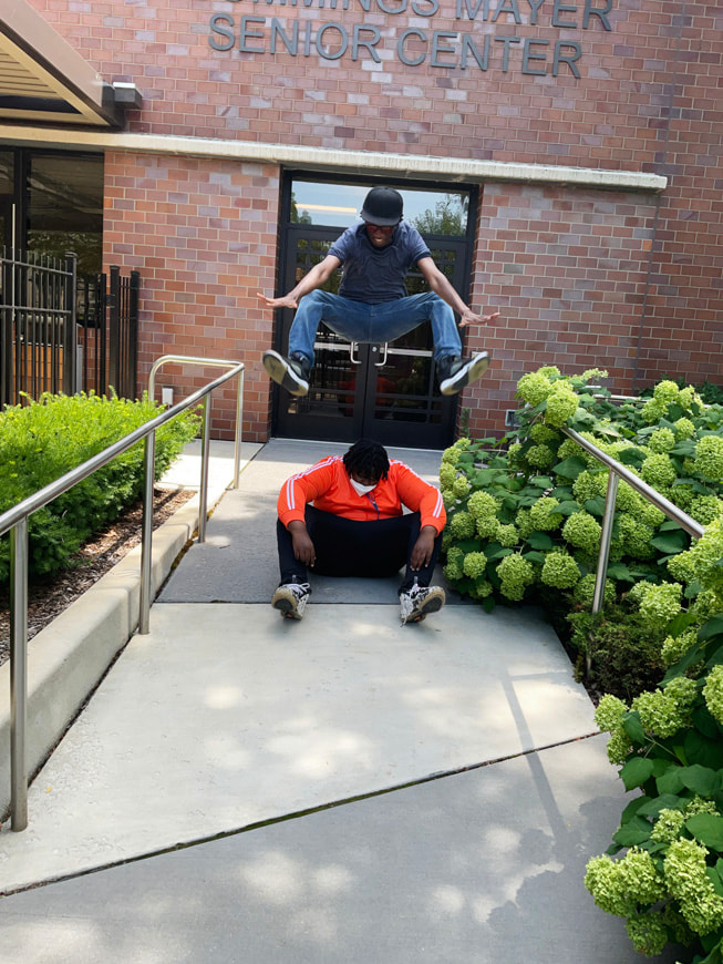 Gisselle Ayala’s action photo shows Glen-David Hardy-Covington and John Johnson in front of a senior centre.