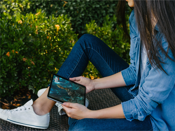 Dışarıda iPad’inden film izleyen bir kadın.
